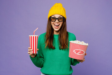 Young surprised fun woman wear green sweater yellow hat casual clothes 3d glasses watch movie film...