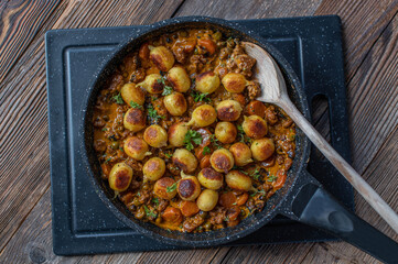 Creamy beef with peas, carrots and gnocchi in a frying pan