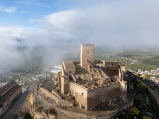 el hermoso castillo de Alcaudete rodeado por un banco de niebla, Andalucía	