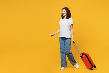 Sideways traveler woman wear t-shirt casual clothes hold suitcase bag walk go isolated on plain yellow background Tourist travel abroad in free spare time rest getaway Air flight trip journey concept
