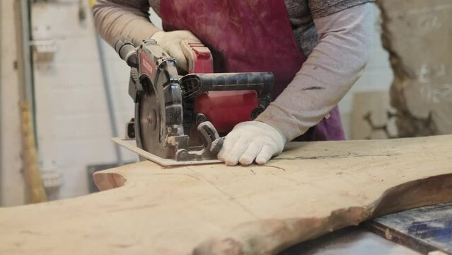 Craftsperson uses an electric planer on wood, showcasing skill. The image connects to the rise in upcycling and repurposing wood.