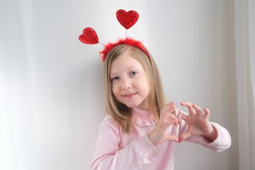 A little girl making hearts out of her hands, love, Valentine's day, showing a heart-shaped sign...