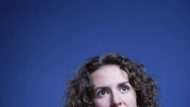 Top of young thoughtful woman opening eyes upwards thinking and problem-solving with blue backdrop good to animate bubble idea imagination