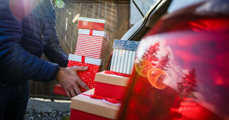 man packing Christmas gift boxes in car