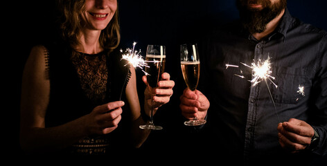 couple holding sparkles and champagne glasses Happy New Year