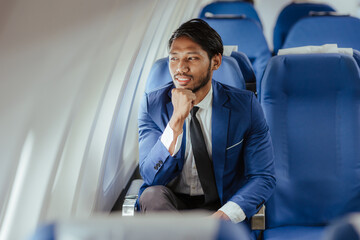 Young businessman sitting in airplane using laptop and smart phone