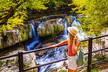 A woman, a girl tourist, enjoys a picturesque view of the Martvili Canyon. The blonde stands on the observation deck of the Martvili Canyon. Georgia, Martvili