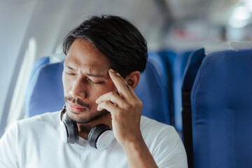 headache on airplane Male passenger is afraid and feels bad while flying on an airplane.