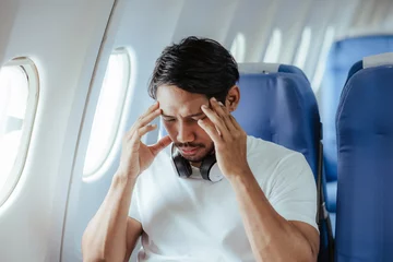 Fotobehang headache on airplane Male passenger is afraid and feels bad while flying on an airplane. © Witoon