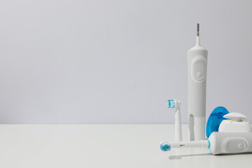Electric toothbrush and dental floss on white background, space for text