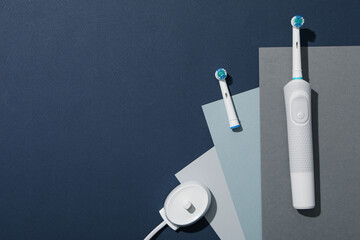 Electric toothbrush and papers on blue background, space for text