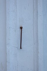 Closeup of a old metal door hook hanging from the wall of a wooden building.