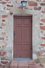 Old brown wooden door on a stone building.