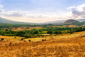 panoramic farmland view of yellow field with sceniv valley , mountains and amazing cloudt sunset