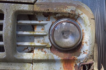 Closeup of an dirty front head lamp on an abandoned car.