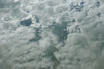 Reflection of cloudy sky on calm sea surface.