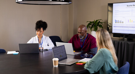 Diverse male and female medical staff with laptops working at office meeting