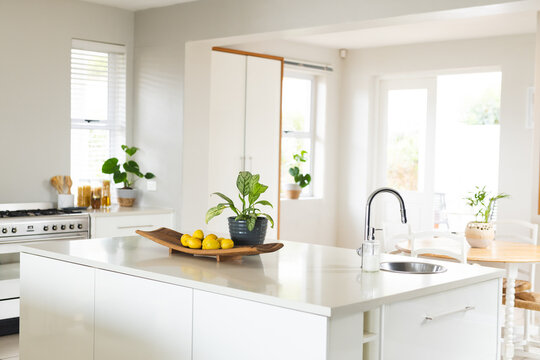 Kitchen island, sink, gas stove, furniture and large windows in sunny kitchen at home