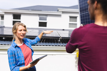 Happy diverse couple installing solar panels and using tablet in sunny garden, copy space