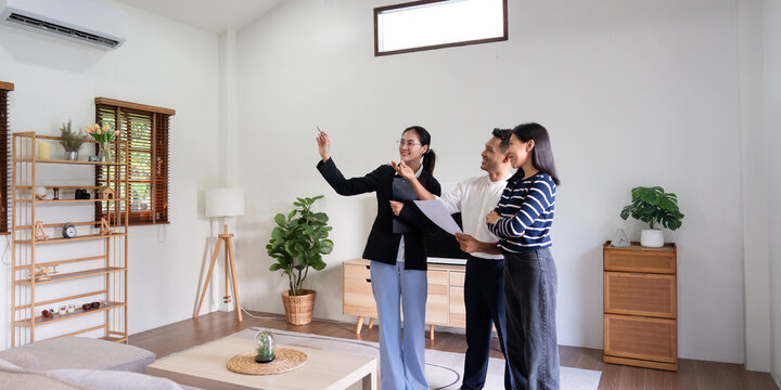 Young couple follow a real estate agent who is giving them a tour around a home, showing all the room and telling about all the advantage of living. Buying house or apartment concept