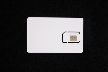 White SIM card isolated on black background. SIM card for mobile phone, top view, close up