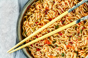 Instant noodles and chopsticks on a light background. Noodles in a plate, top view.