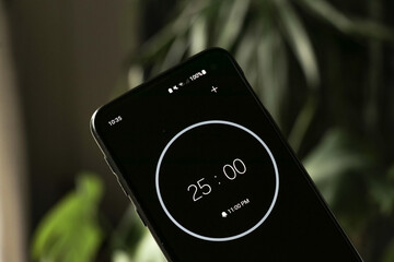 A phone with a black and white 25-minute timer to study with the pomodoro method on a blurry background