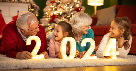 Children celebrating New Year with grandparents holding numbers 2024