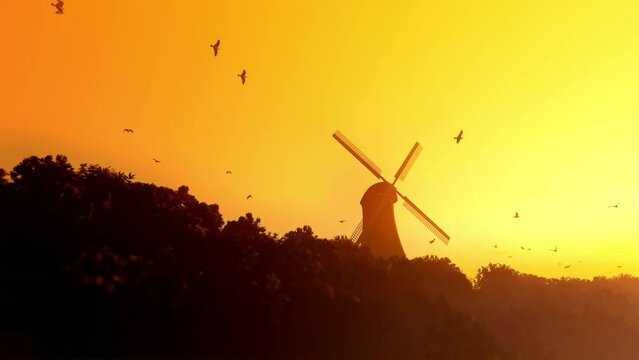 Dutch windmill with pigeons flying against yellow sky at sunset, tilt