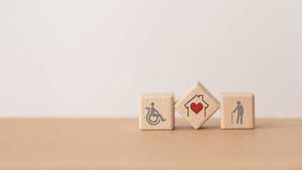 house with red heart  inside  wooden cube block and elderly and disability person icon, including copy space, for home or nursing care for aging people concept - obrazy, fototapety, plakaty