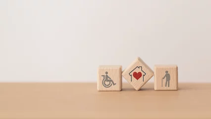 Foto op Plexiglas house with red heart  inside  wooden cube block and elderly and disability person icon, including copy space, for home or nursing care for aging people concept © Ratana21