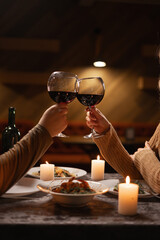 Close up of couple clinking and drinking with glasses of red wine at restaurant