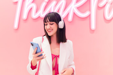 Smiling Asian woman in headphones using smartphone