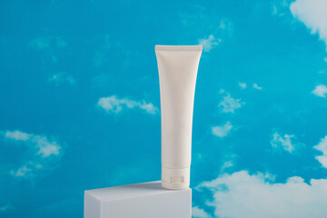 Plastic white tube for cream or lotion. Skin care or sunscreen cosmetic on blue sky background.