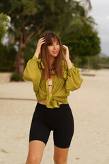 Naklejka premium Attractive brunette woman in stylish casual summer outfit posing on the tropical beach during vacations.
