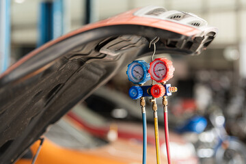 Car mechanic working in auto repair shop, inspecting the operation of the car's air conditioner and...