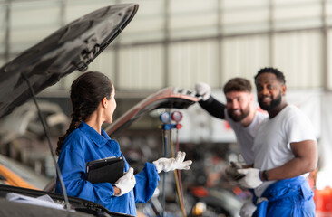 Car mechanic working in an auto repair shop, inspecting the operation of the car's air conditioner and refrigerant, Focus on woman