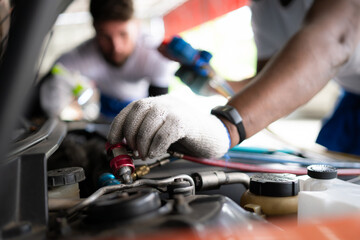 Car mechanic working in an auto repair shop, inspecting the operation of the car's air conditioner and refrigerant.