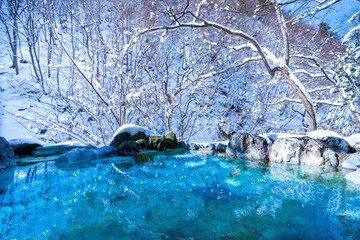 Japanese Hot Springs Onsen Natural Bath The mountain background is covered with a lot of snow. In winter in Japan - obrazy, fototapety, plakaty