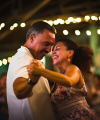 A happy Cuban couple dances traditional salsa at a night celebration - obrazy, fototapety, plakaty