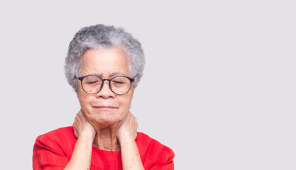 Senior woman suffering from neck pain standing on a gray background.