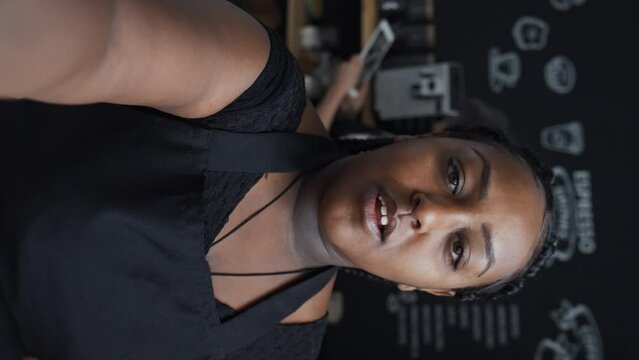 Vertical POV shot of female barista vlogging her day in life as coffee shop worker, talking about her occupation and colleagues