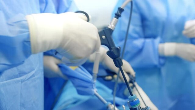 This detailed video captures a live laparoscopic surgery being performed by skilled surgeons in a modern operating room. The medical team, dressed in sterile blue gowns and gloves, uses advanced lapar