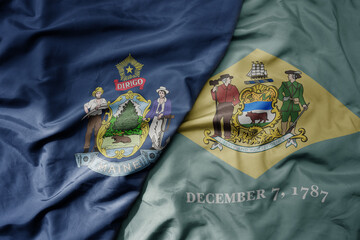 big waving colorful national flag of delaware state and flag of maine state .