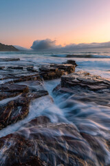 Ocean water flows through rock platforms on the coastline.