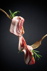 Bacon slices and rosemary on a fork.