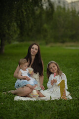 With the softness of the evening light enveloping them, a mother and her children share a quiet moment of affection, highlighting the universal theme of familial love and togetherness.