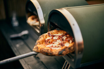 Close-up of a freshly baked pizza, getting right from the oven. - obrazy, fototapety, plakaty