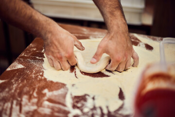 Focus on the male hands, sharpening a pizza dough, using flour.