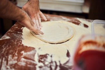 A pizza master holding a pizza dough, making a shape, using flour.